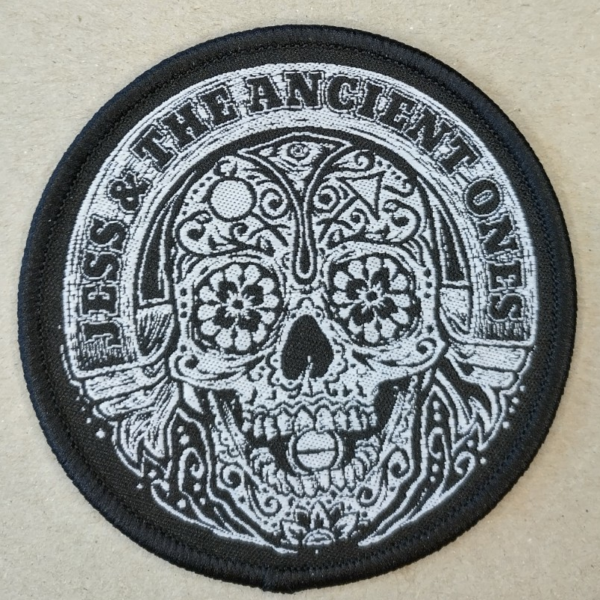 Round shape sleeve patch live pic on grey background with text on up Jess & the Ancient Ones. Scull in the middle.